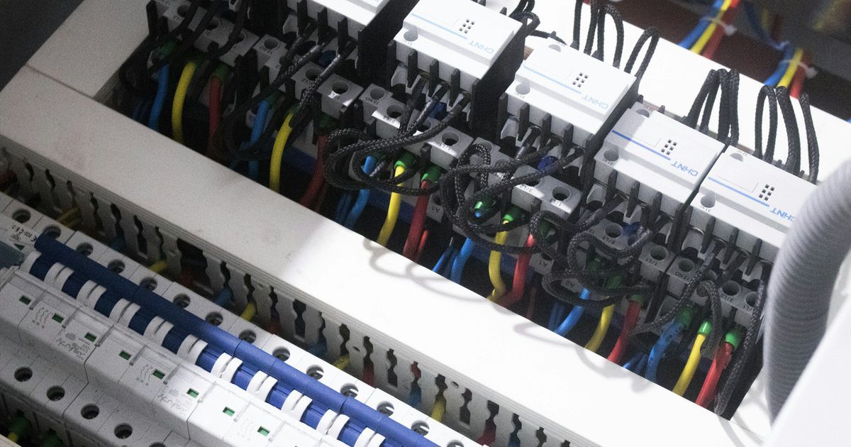 A roadside utility cabinet standing open with its terminal blocks and wiring bundles exposed.