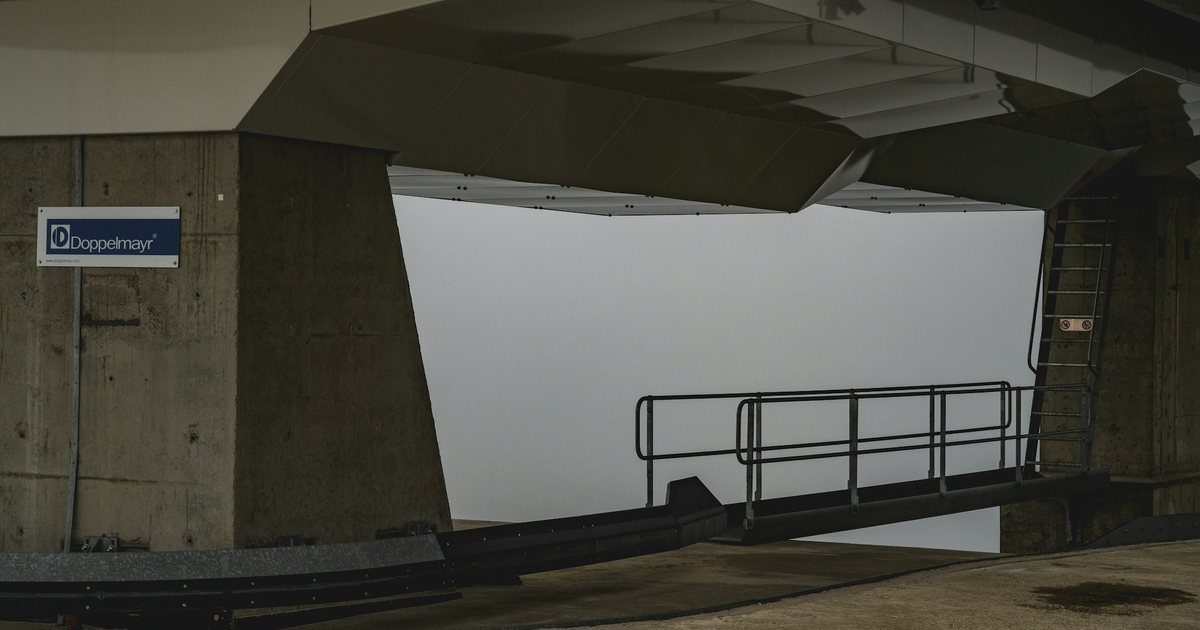 A concrete service ramp descending beneath a large building toward a goods entrance below street level.