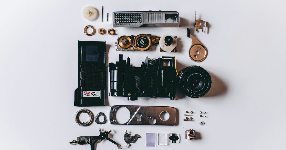 A machine opened on a workbench, its casing removed and internal assemblies and wiring exposed layer by layer.