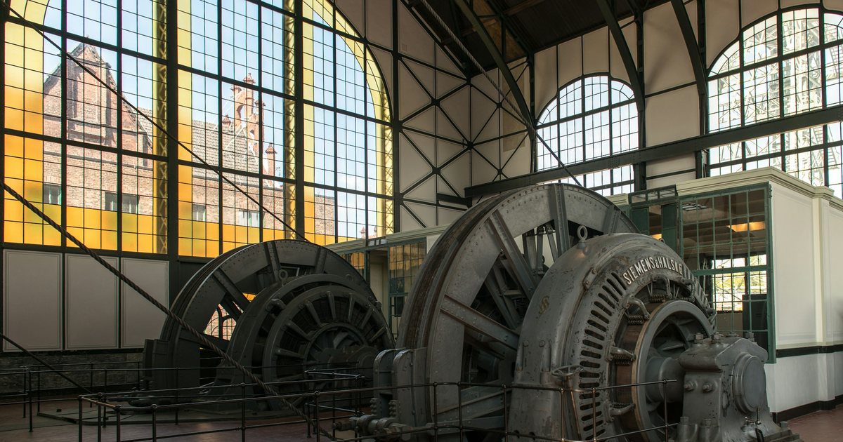 The interior of a power station turbine hall, steel stairs and gantry walkways stacked through several levels.