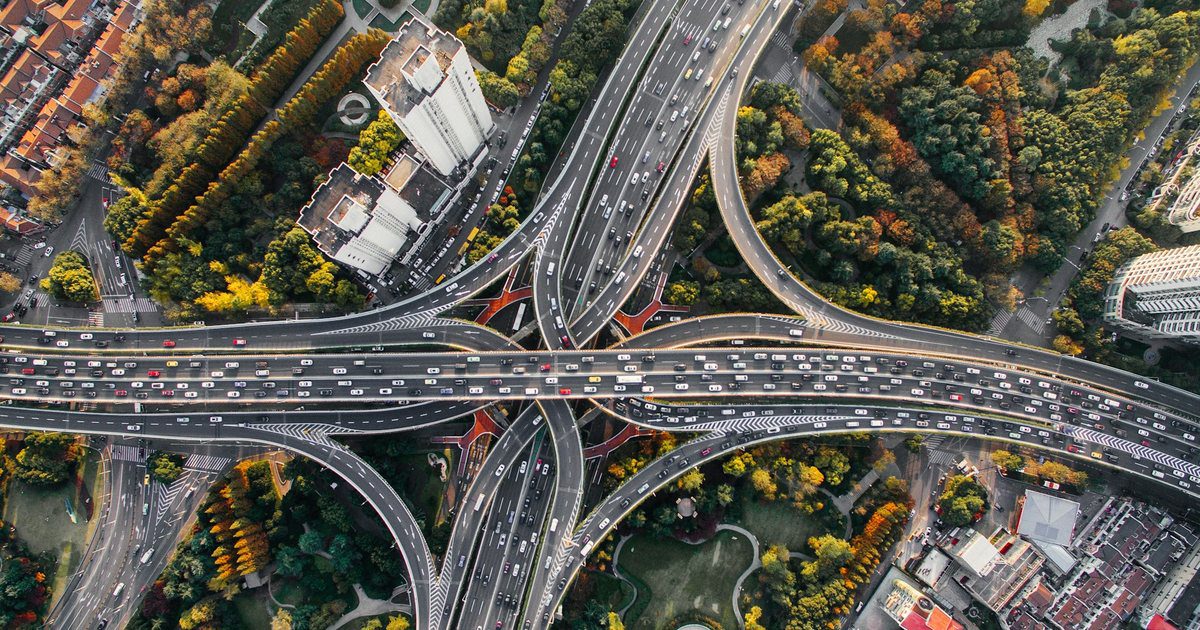 An aerial view of a motorway interchange where one carriageway splits and curves away onto a separate ramp.