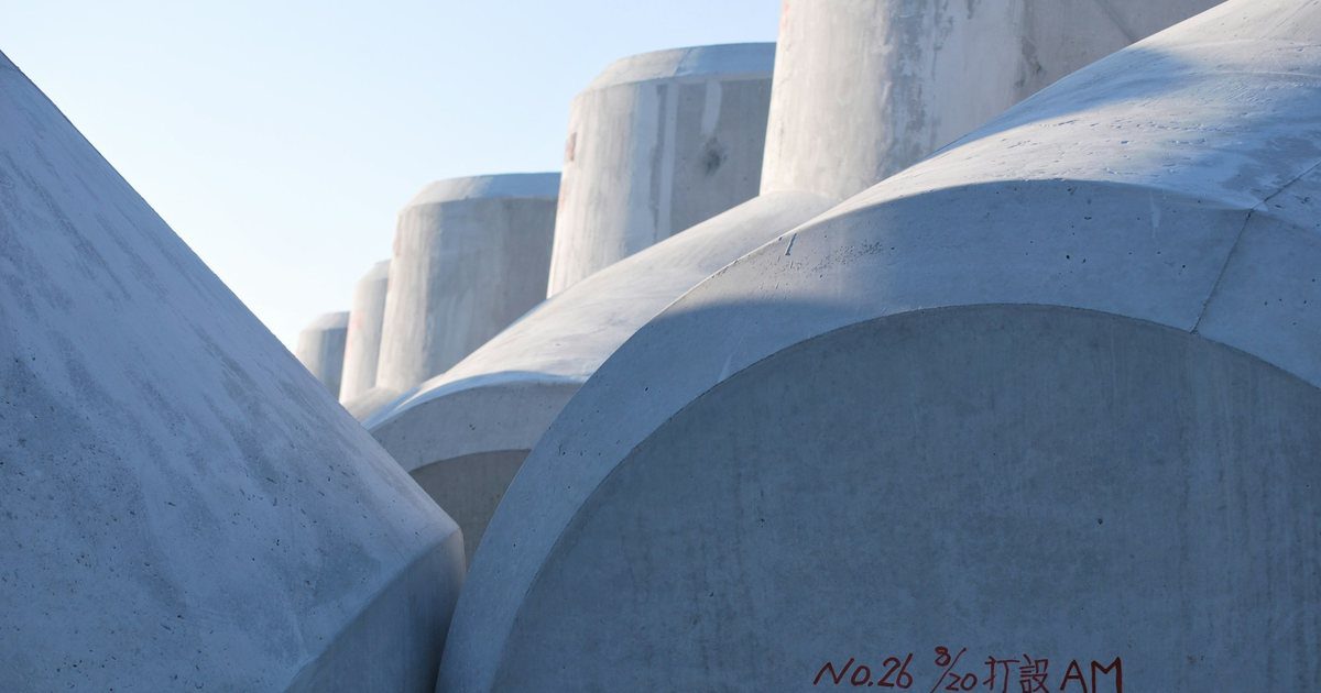 Interlocking concrete armour blocks along a harbour breakwater with waves breaking against them.